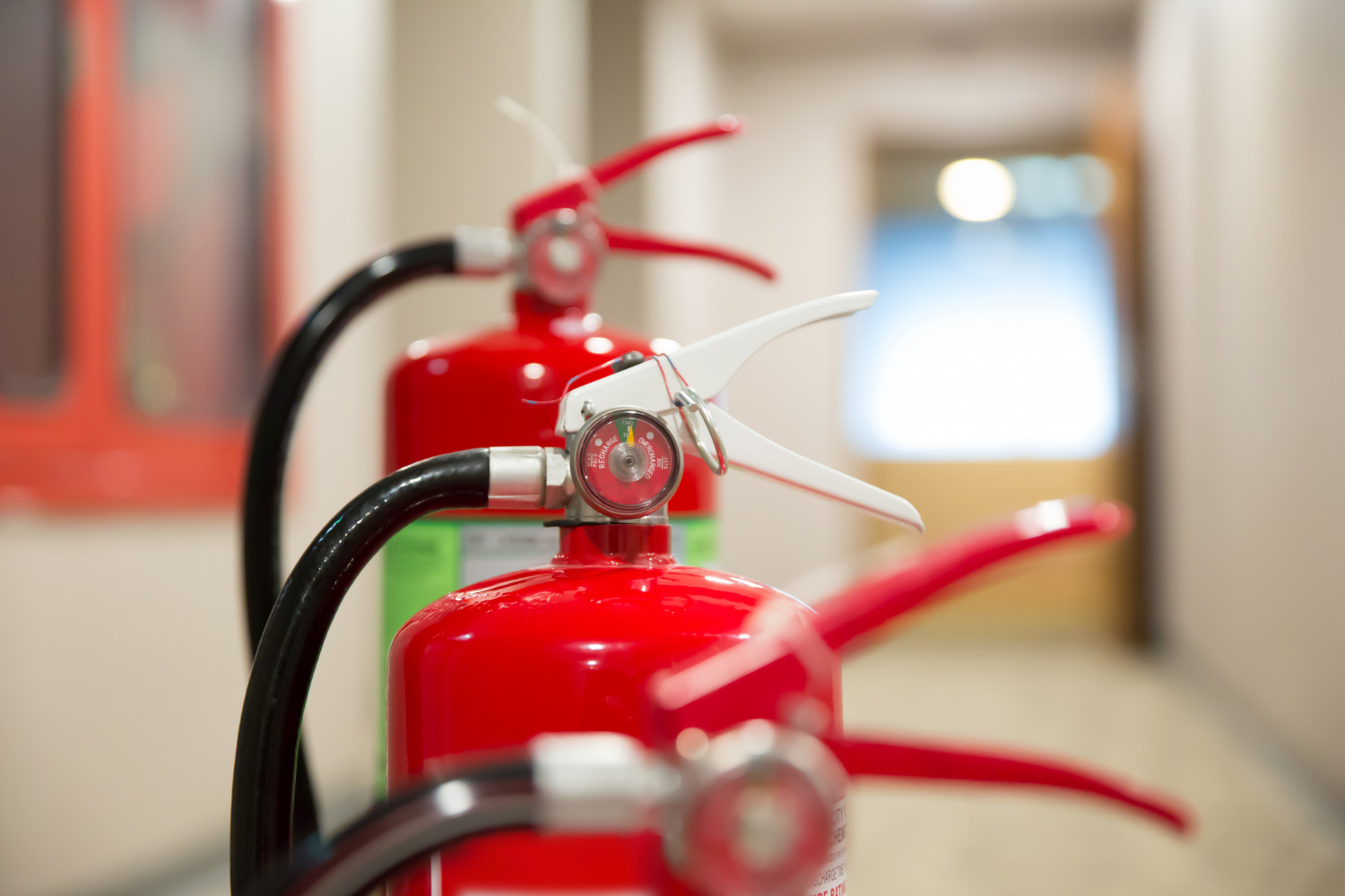 Gros plan sur plusieurs extincteurs rouges alignés dans un couloir, symbolisant la prévention et la sécurité incendie en Dordogne.